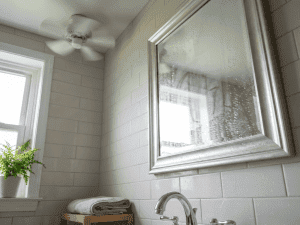 Close-up of a bathroom mirror with light condensation and water droplets on tile in a Chicago suburban home, showing how moisture buildup leads to mold.